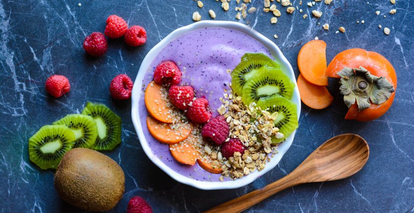smoothie in a bowl with cut fruit and spoon