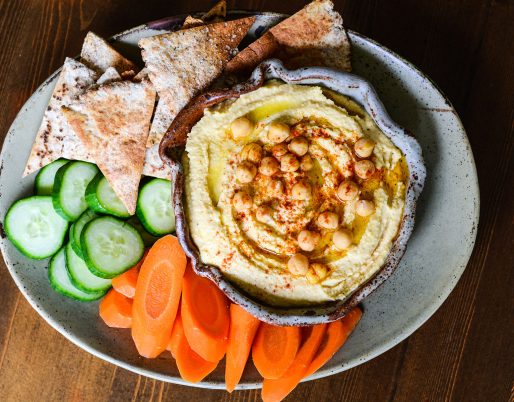 hummus in bowl with veggies and pita